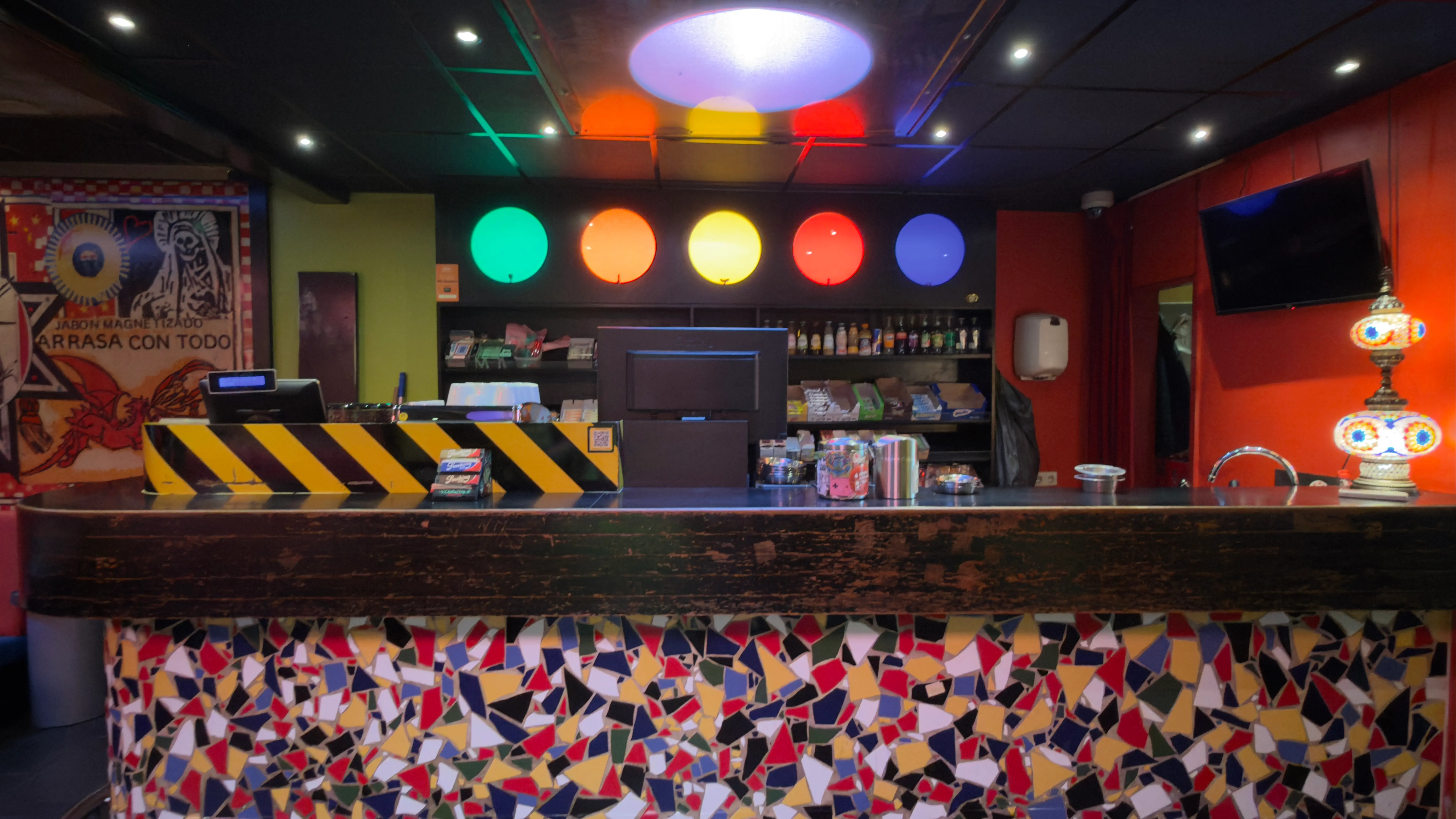 De bar van Coffeeshop Rokade — een rij gekleurde lichtschijven boven een mozaïekfront